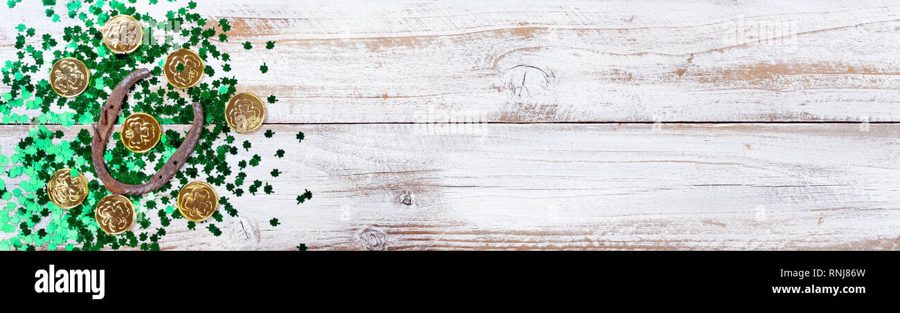 Colore verde brillante shamrock con monete d oro e rusty a ferro di cavallo per San Patrizio giorno su bianco rustico sfondo di legno Foto Stock