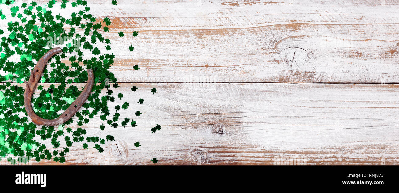 Colore verde brillante shamrock e rusty a ferro di cavallo per San Patrizio giorno su bianco rustico sfondo di legno Foto Stock