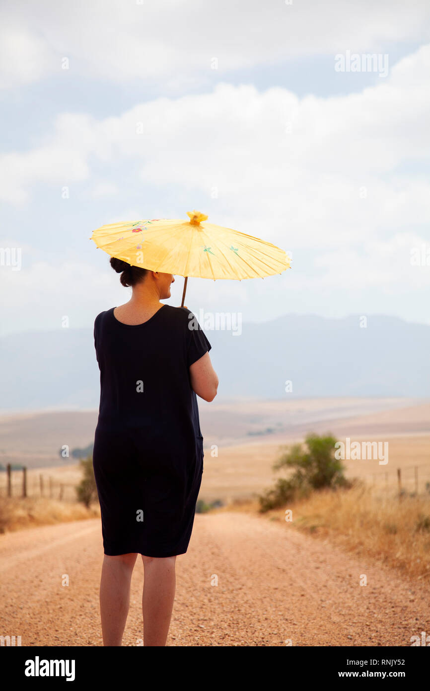 Donna matura in abito nero con ombrello in campagna Foto Stock