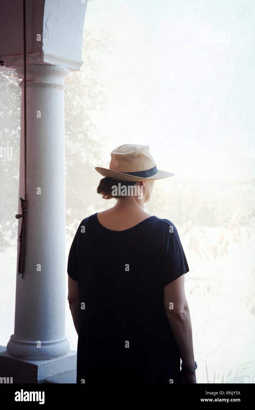 Donna in abito nero e il cappello in piedi da pilastri Foto Stock