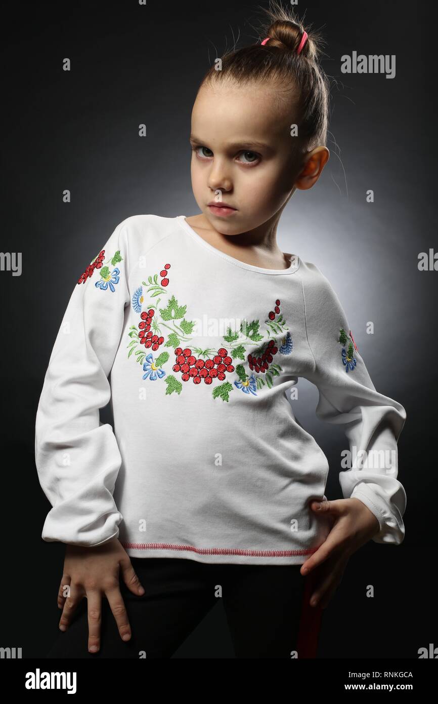 Ragazza Ucraina 5-9 anni, in una camicia ricamata con i capelli raccolti con fiducia dimostra la sua indipendenza e serietà Foto Stock