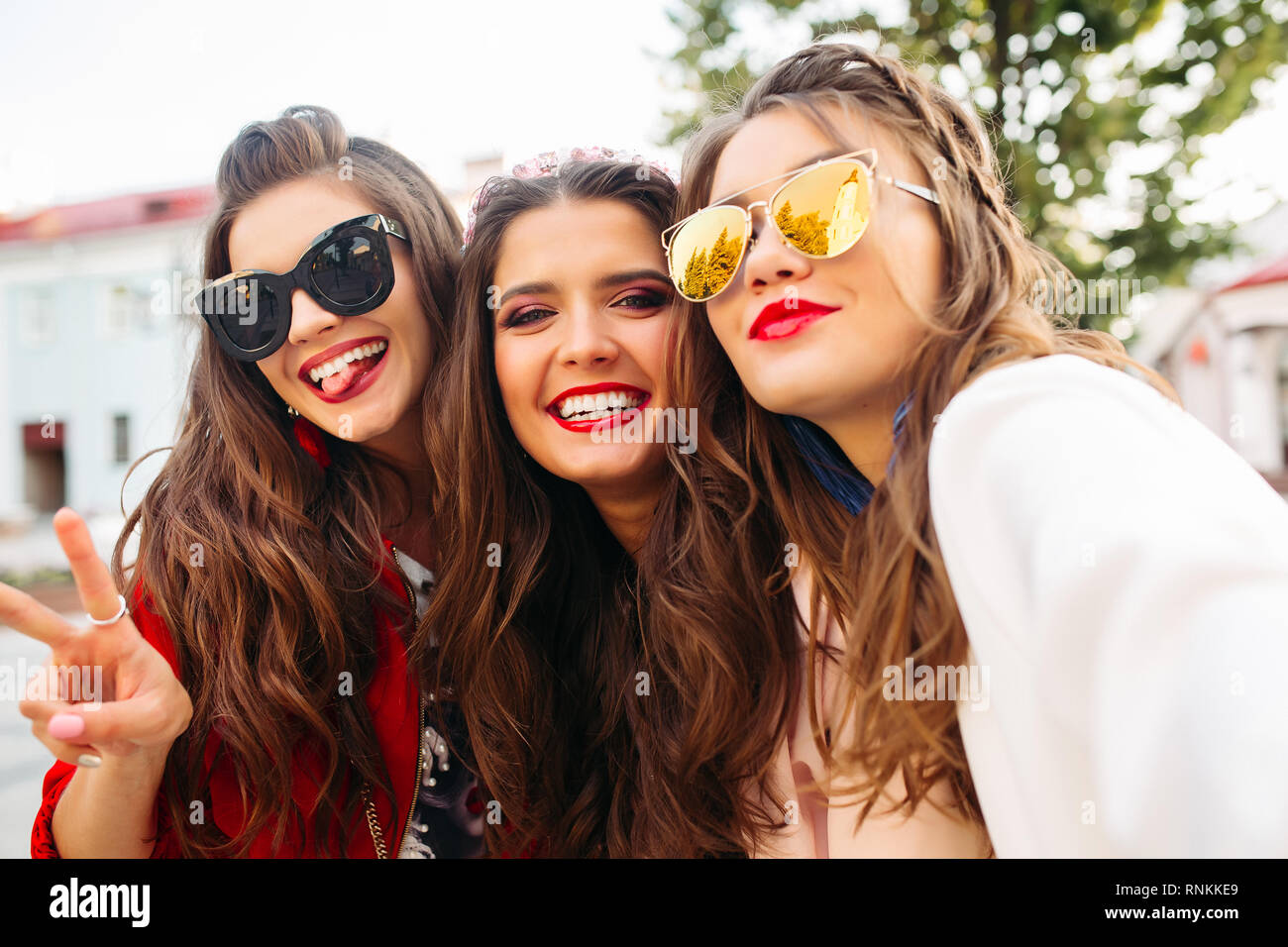 Belle ragazze in occhiali da sole che mostra segni di pace in telecamera con  sorriso Foto stock - Alamy