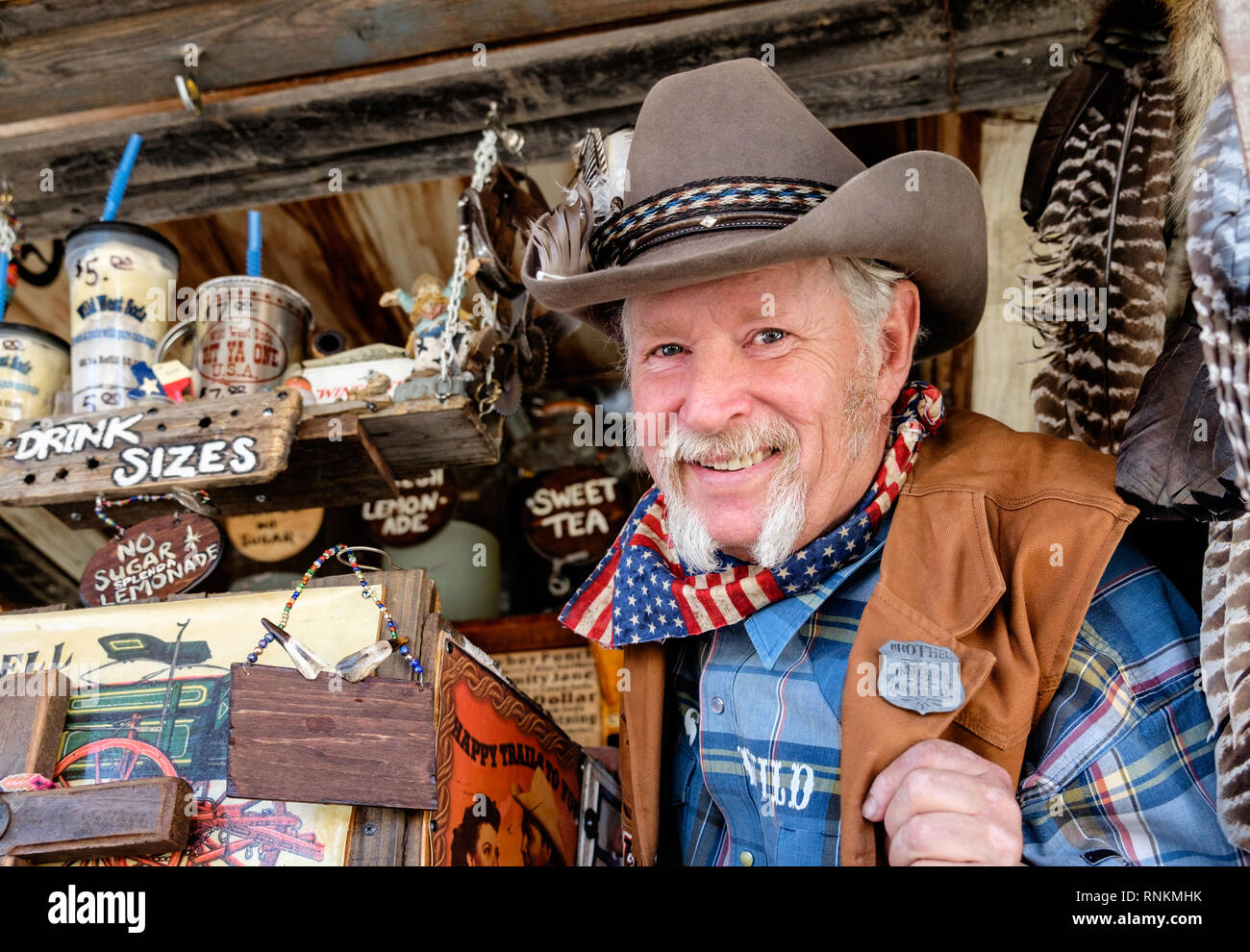 Staycation. Sorridente cowboy texano con cappello cowboy, sciarpa e baffi  bianchi a ferro di cavallo al mercato Wild West Soda. Trade Days Market  Foto stock - Alamy
