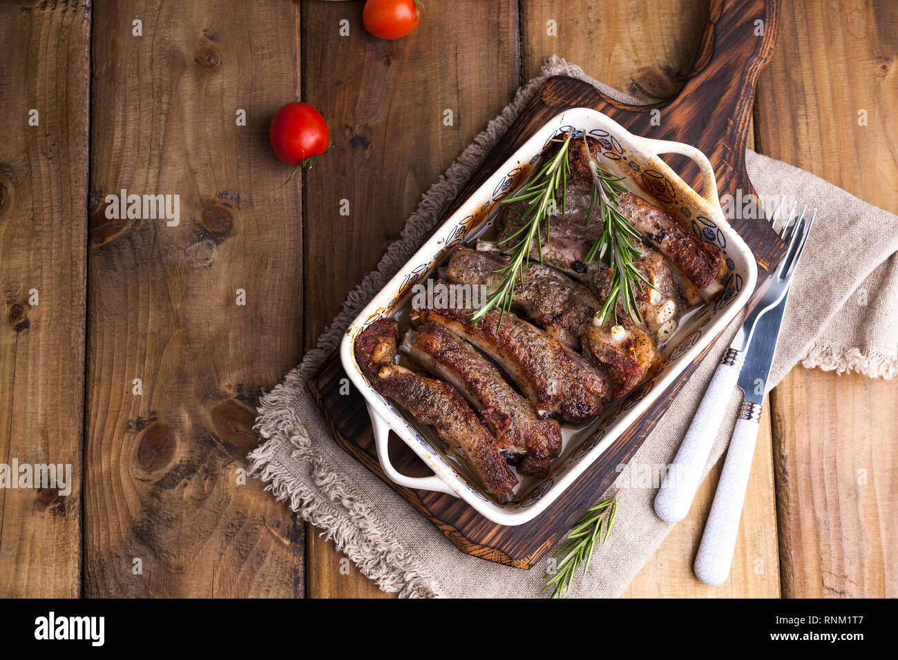 Costolette di maiale alla griglia. Carne con spezie ed erbe in piatti su sfondo di legno. Pranzo barbecue con insalata e salsa. Spazio libero per il testo Foto Stock