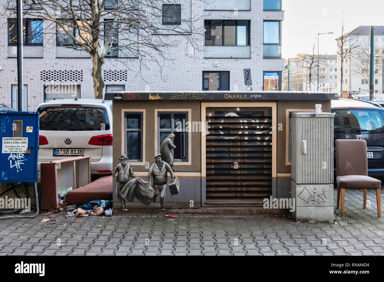 Berlino, Mitte. Urban ancora in vita. Utility box con la pittura di persone in fuga da Berlino Est e abbandonata mobili in dumping, poltrona letto e Foto Stock