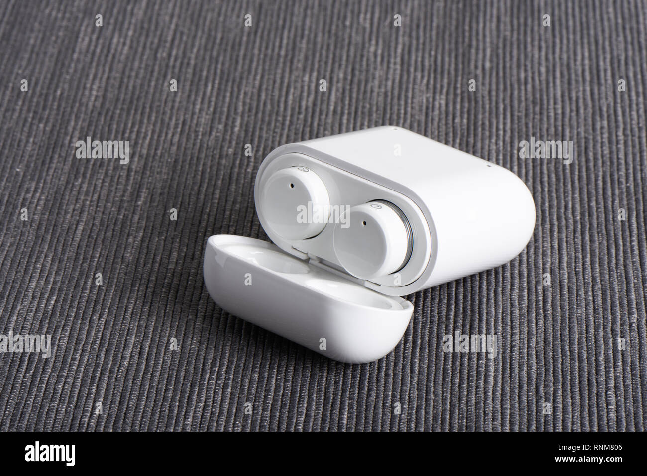 Wireless bluetooth cordless auricolari con custodia a pagamento su un sfondo di tessuto Foto Stock