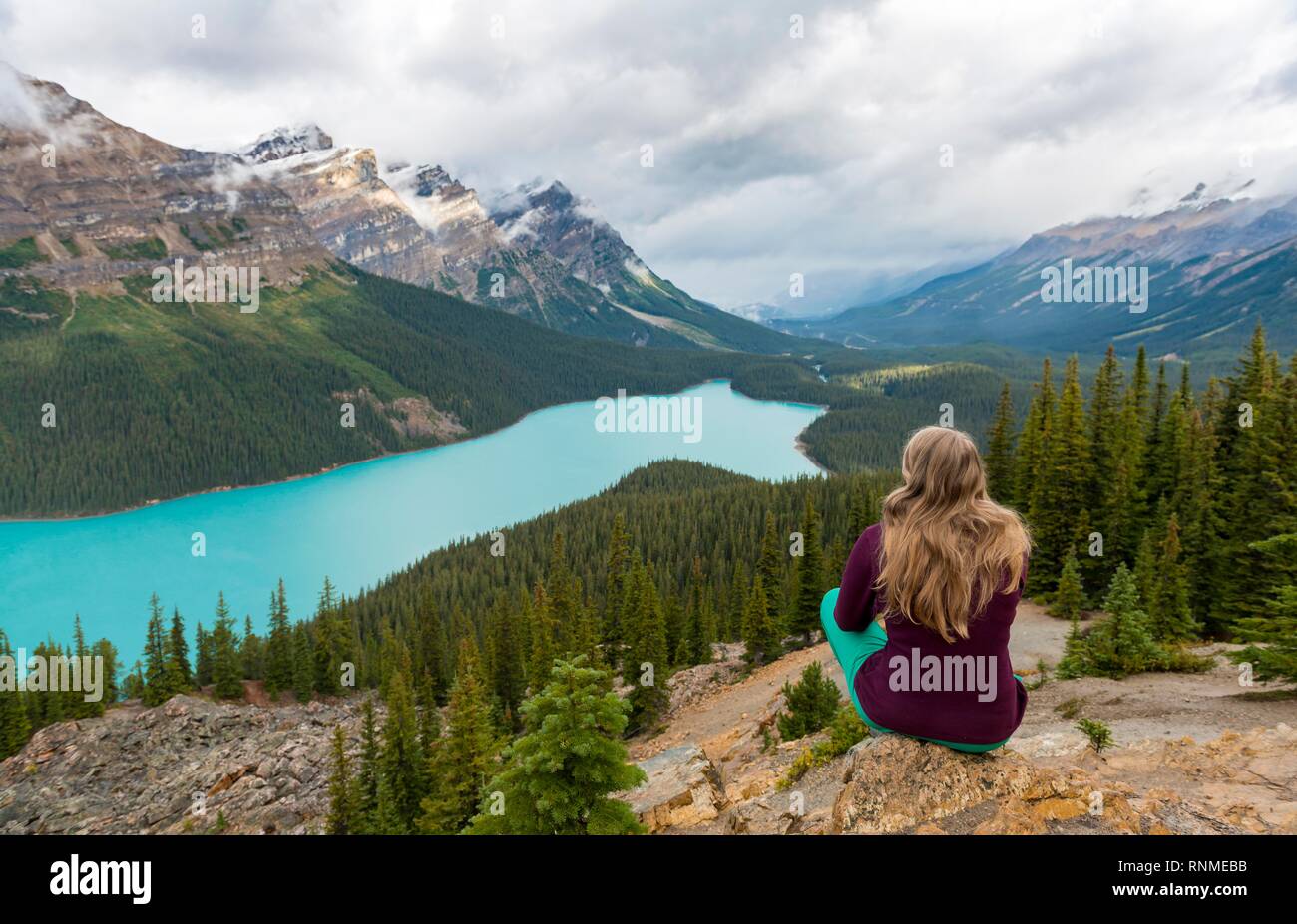 Giovane donna seduta su una pietra cercando in natura, turchese, Lago Peyto Lake, Montagne Rocciose, il Parco Nazionale di Banff, provincia di Alberta, Canada, Nord Foto Stock