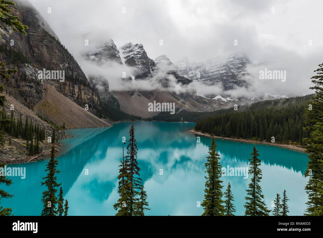 Nuvole e sospesi tra le cime della montagna e la riflessione in turchese lago glaciale, Moraine Lake, Valle dei Dieci Picchi, montagne rocciose, Banff Nationa Foto Stock