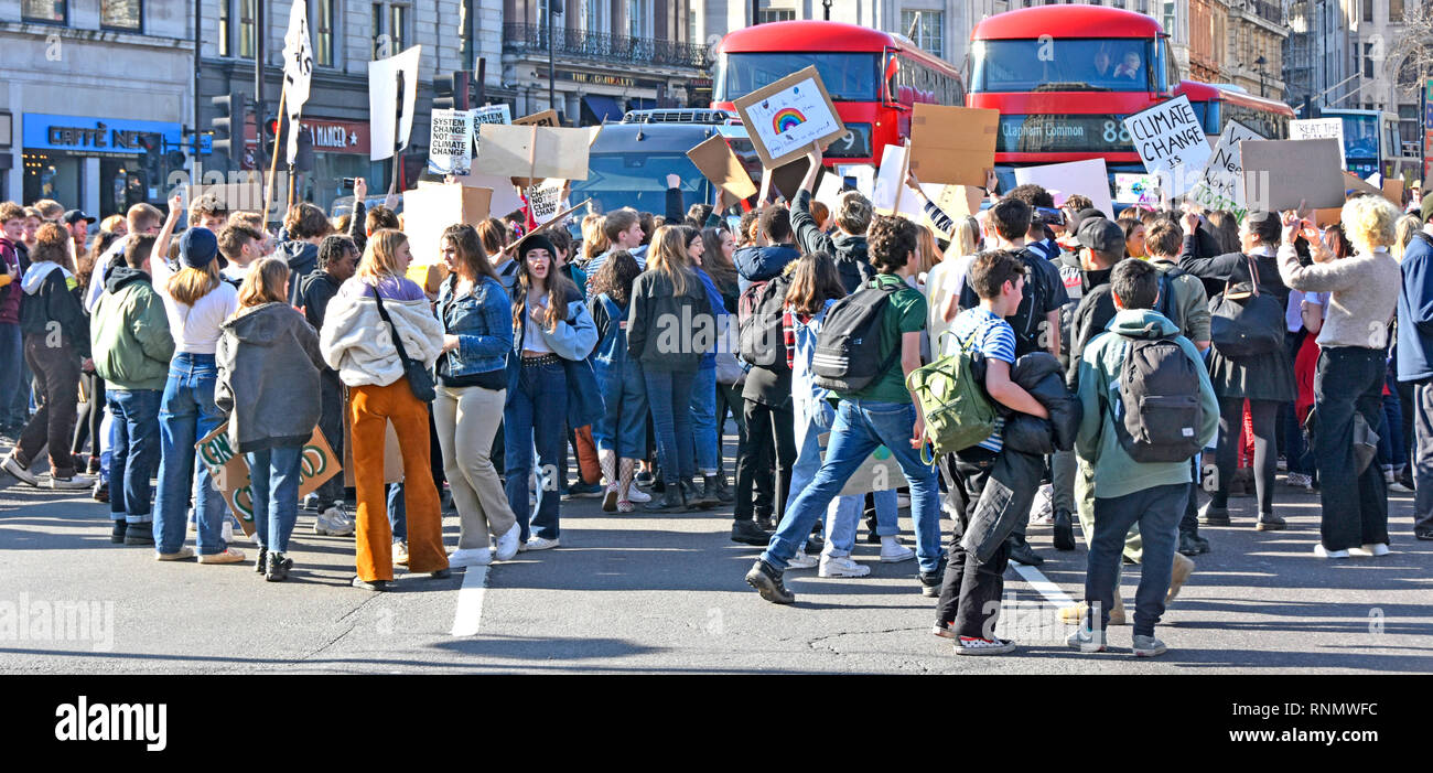 Gruppo di adolescenti scuola bambini kids scuola di miss di Sciopero e protesta sul cambiamento climatico targhetta d'onda & chant bloccando il traffico stradale Londra Inghilterra REGNO UNITO Foto Stock