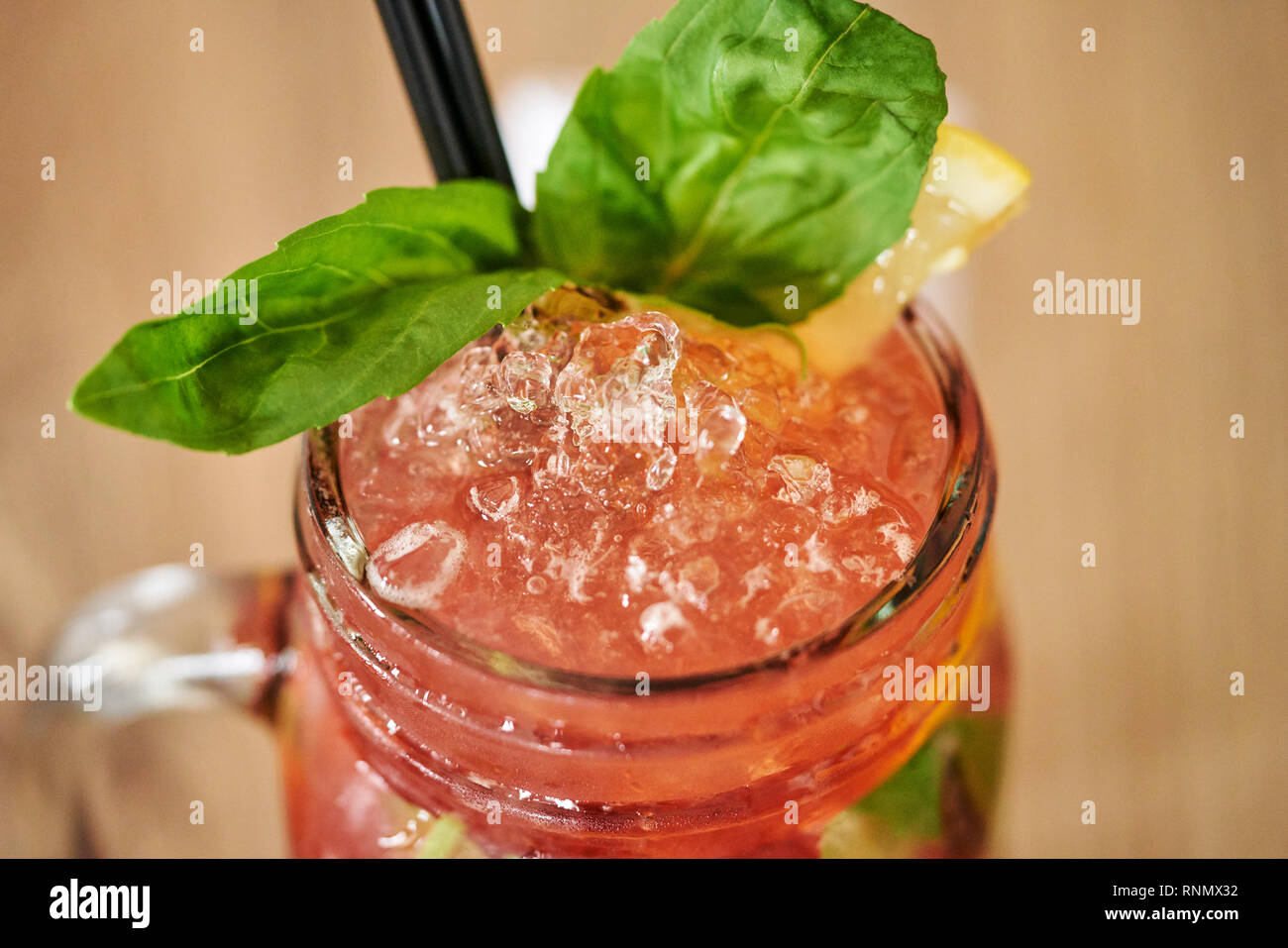 Chiusura del freddo rinfrescante lampone limonata con basilico in Mason Jar con ghiaccio su sfondo di legno Foto Stock