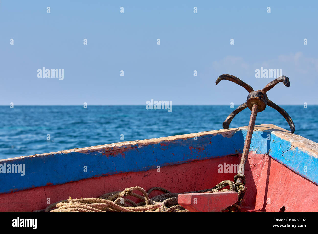 Vista della prua di una vecchia barca di legno a vela. Ancoraggio di metallo, mare o oceano sotto il cielo blu chiaro. Foto Stock