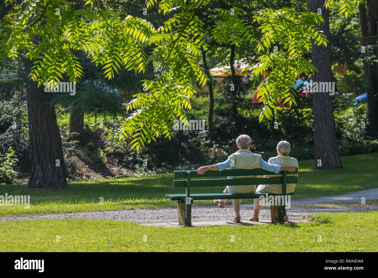 Coppia di anziani godendo di sole di primavera su una panchina nel parco, Germania Foto Stock