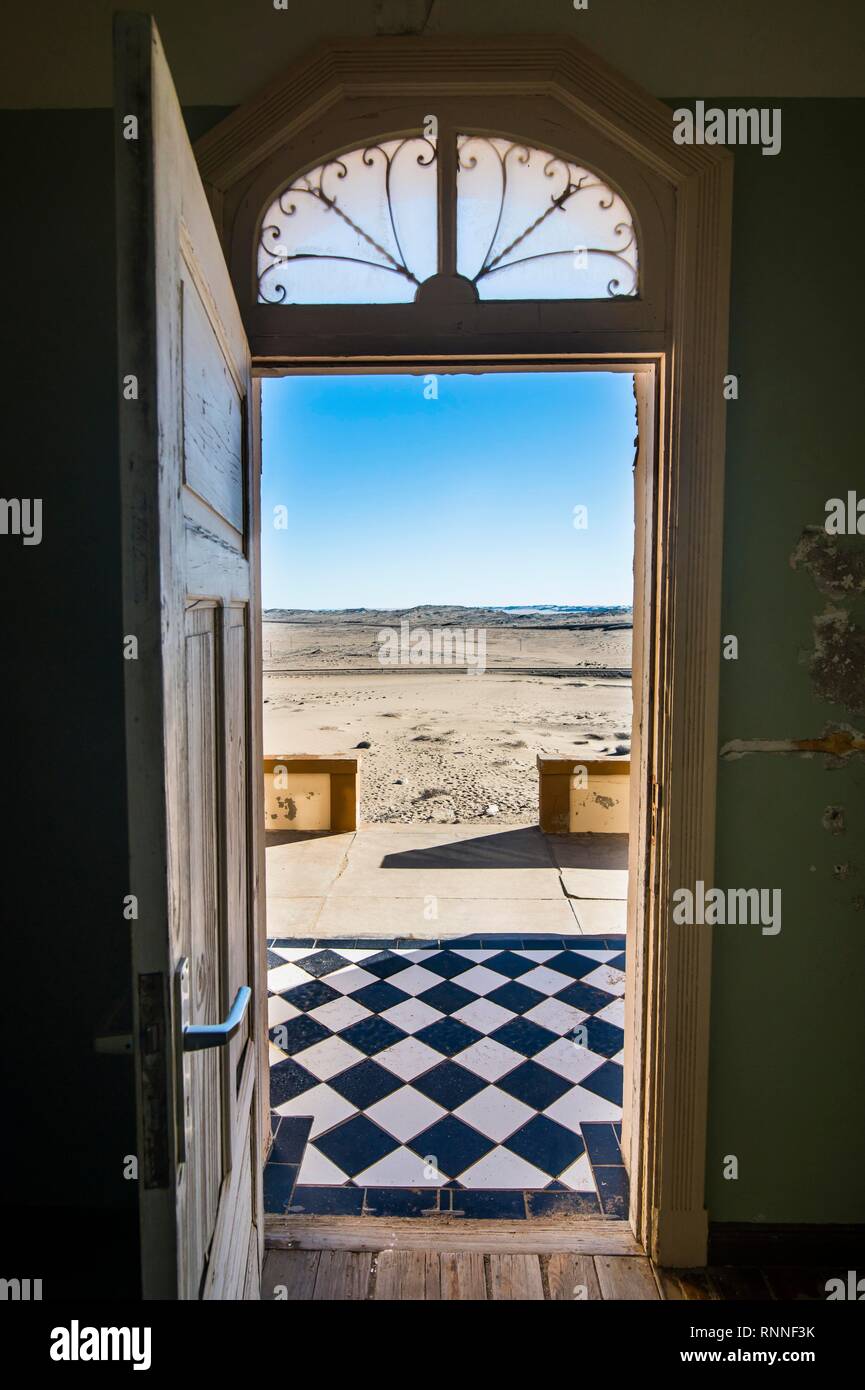 Guardando attraverso un doorinto il dessert, antica città mineraria Kolmanskop o Coleman's Hill, vicino a Lüderitz, Namibia Foto Stock