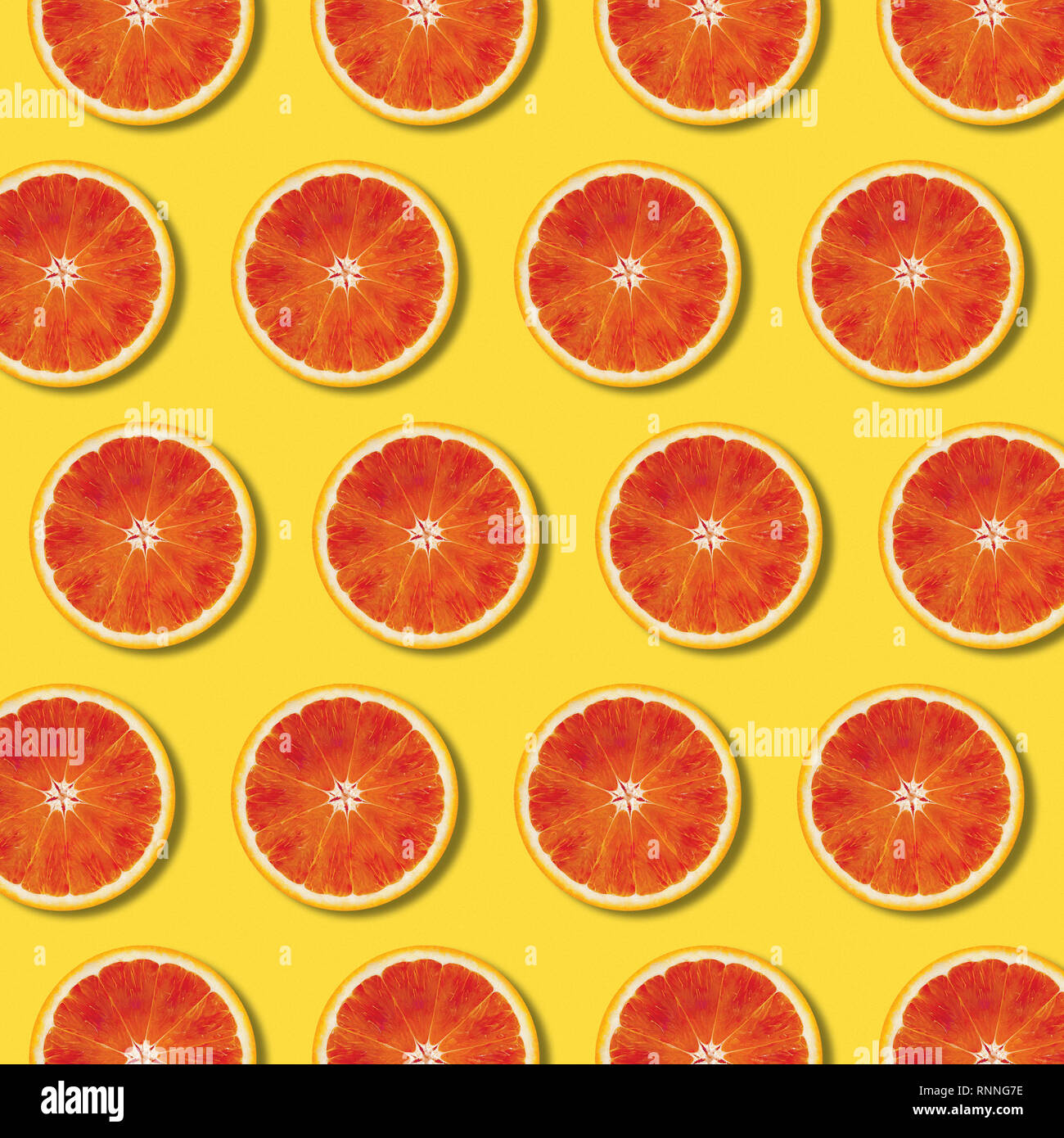 Red fettine di arancia pattern sul giallo il colore dello sfondo. Minima laici flat top view food texture Foto Stock