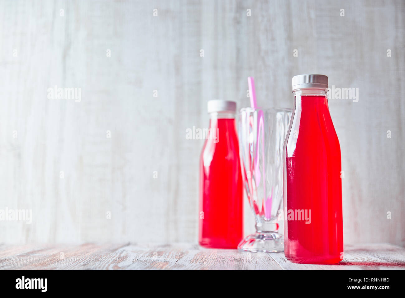 Bottiglia di succo di frutti di bosco su una luce tavolo in legno. rinfrescanti drink estivo di close-up. Foto Stock