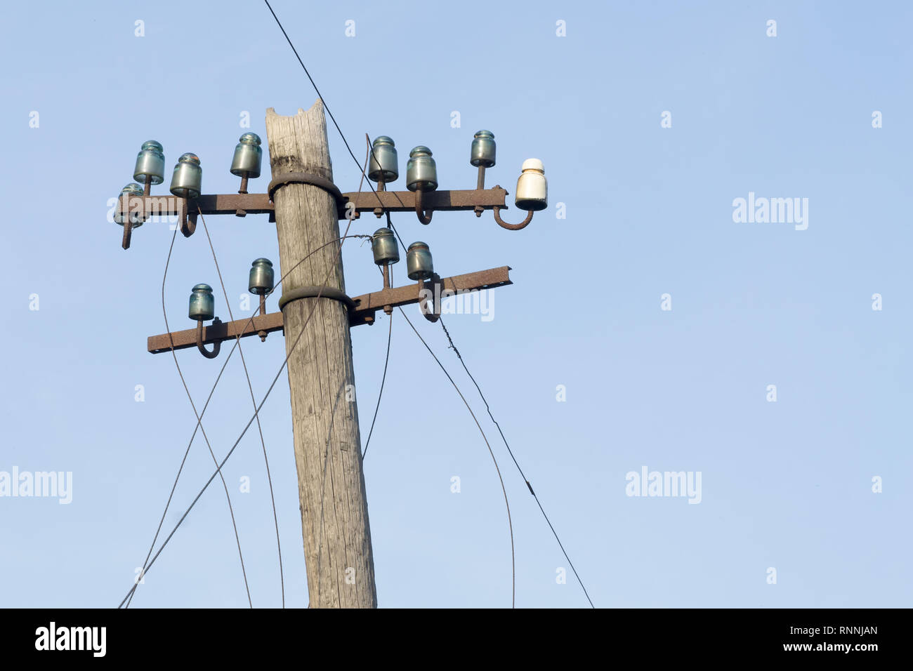 Vecchio elettrico palo in legno con vetro e ceramica Isolatori e fili  elettrici contro il cielo blu. Copia dello spazio Foto stock - Alamy