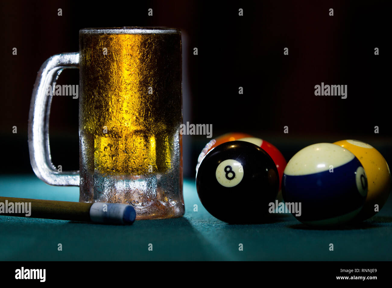 Chiudere fino a freddo isolato congelati boccale di birra con stecche da biliardo palle e su sfondo nero Foto Stock