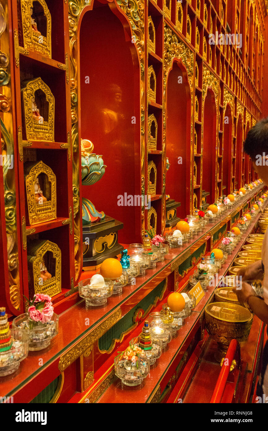 Offerte per il tempio del Dente del Buddha Tempio reliquia, Singapore. Visitatori inserire monete in ciotole di rivestimento del muro. Foto Stock