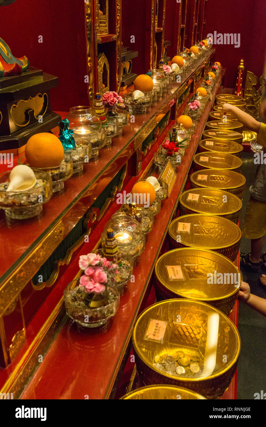 Offerte per il tempio del Dente del Buddha Tempio reliquia, Singapore. Visitatori inserire monete in ciotole di rivestimento del muro. Foto Stock