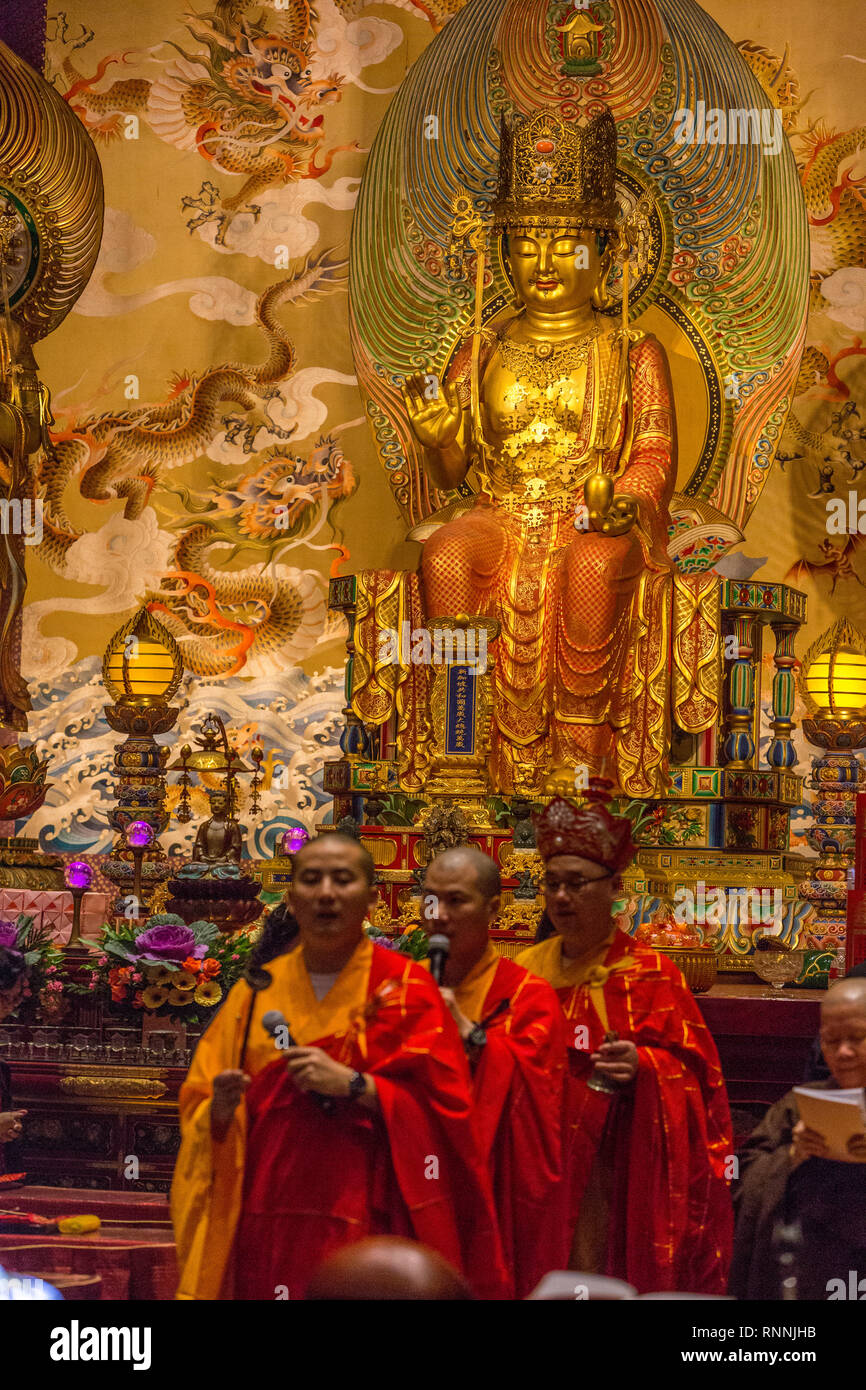 I monaci buddisti di eseguire un rituale nel corridoio principale di preghiera, del Dente del Buddha reliquia Tempio. Buddha Maitreya in background. Foto Stock