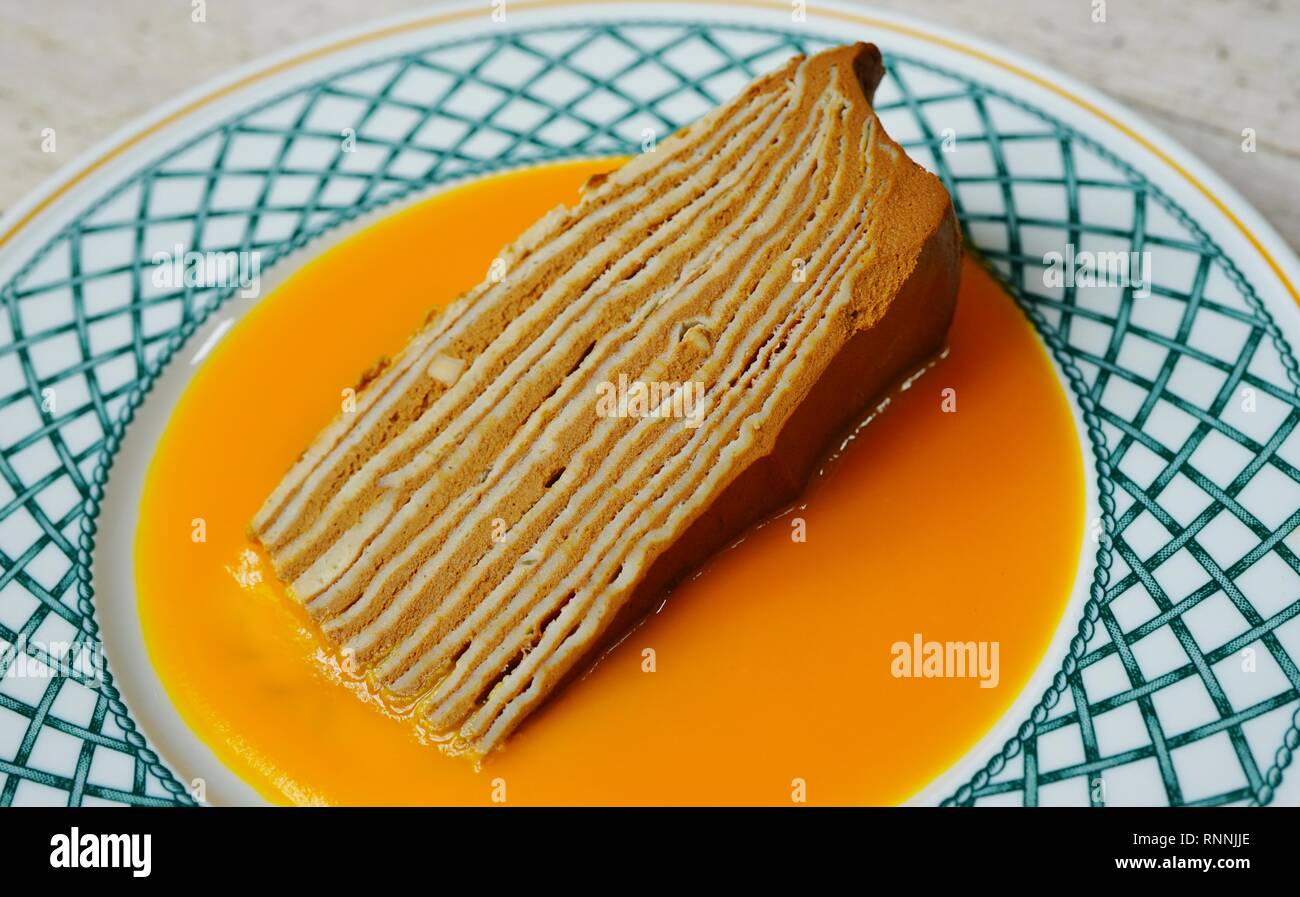 Fetta di strato vegano crêpe dolce con ripieno di cioccolato e coulis di mango Foto Stock