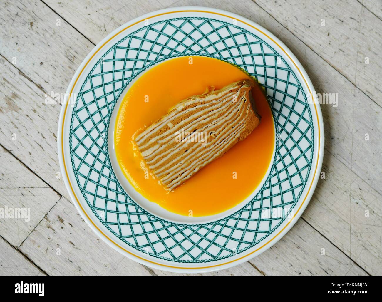 Fetta di strato vegano crêpe dolce con ripieno di cioccolato e coulis di mango Foto Stock