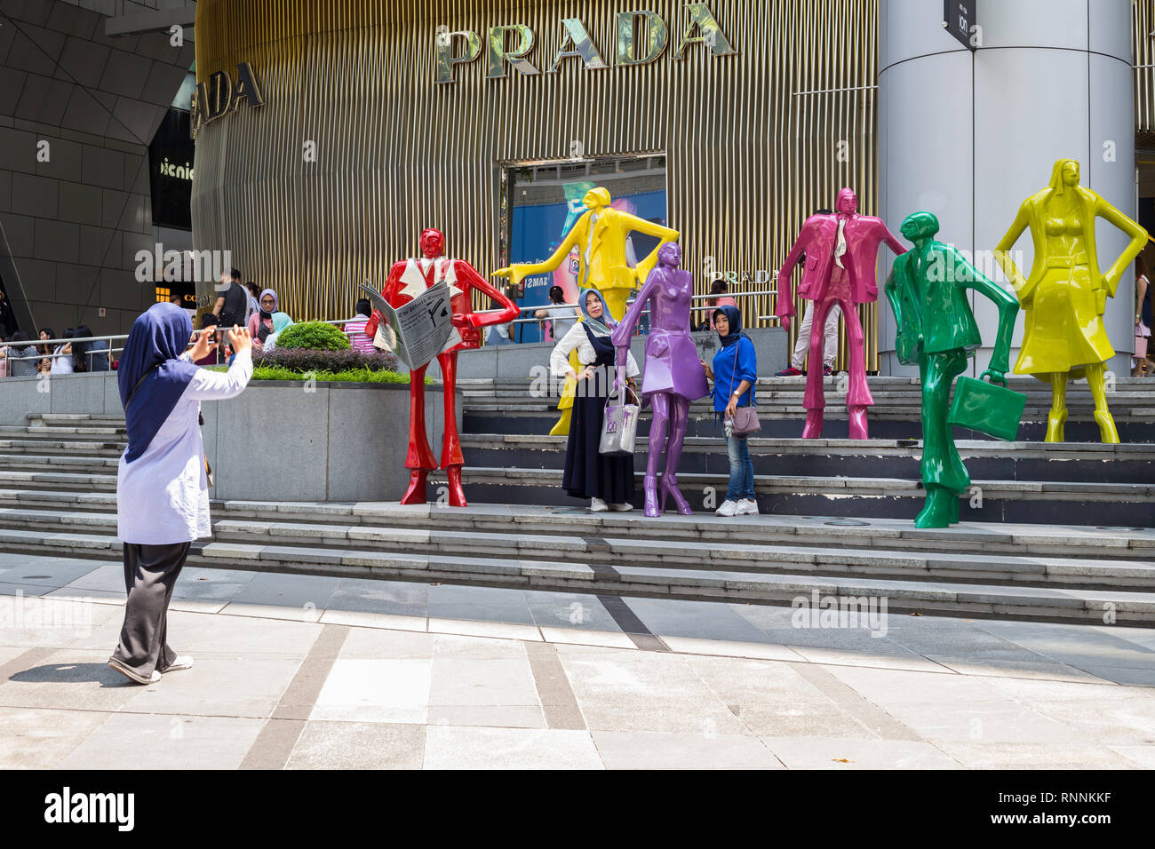 Di Singapore, Orchard Road Street scene. I turisti che posano per una foto in mezzo moderno scultura di moda al di fuori del centro commerciale di ioni. Foto Stock