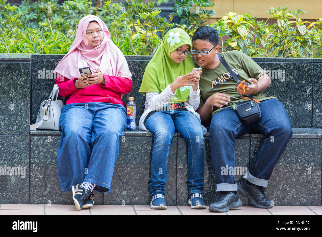 Di Singapore, Orchard Road Street scene. I giovani abitanti di Singapore con i loro telefoni cellulari. Foto Stock