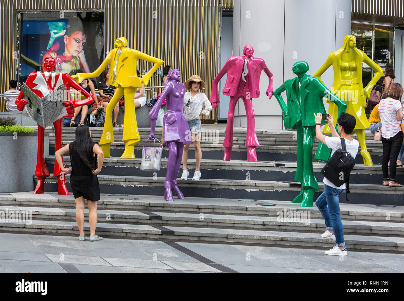 Gli amanti dello shopping rendendo le foto dalle moderne sculture di moda al di fuori del centro commerciale di ioni, di Singapore, Orchard Road Street scene. Persone urbane da Kurt Lorenz Metzler. Foto Stock