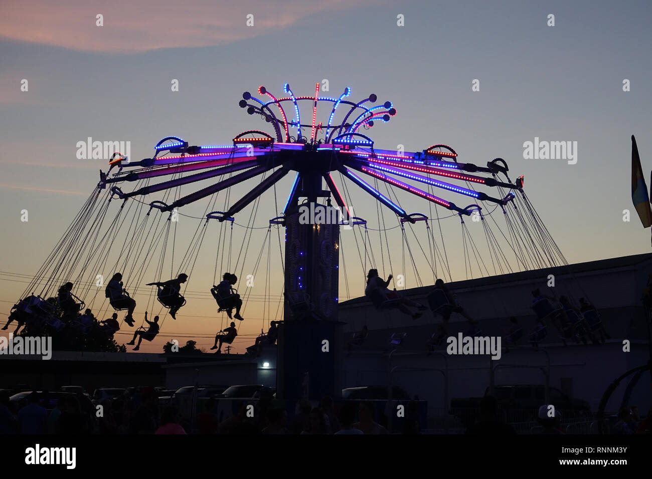 Ruota Panoramica Gigante e oscilla in un parco di divertimenti al tramonto Foto Stock
