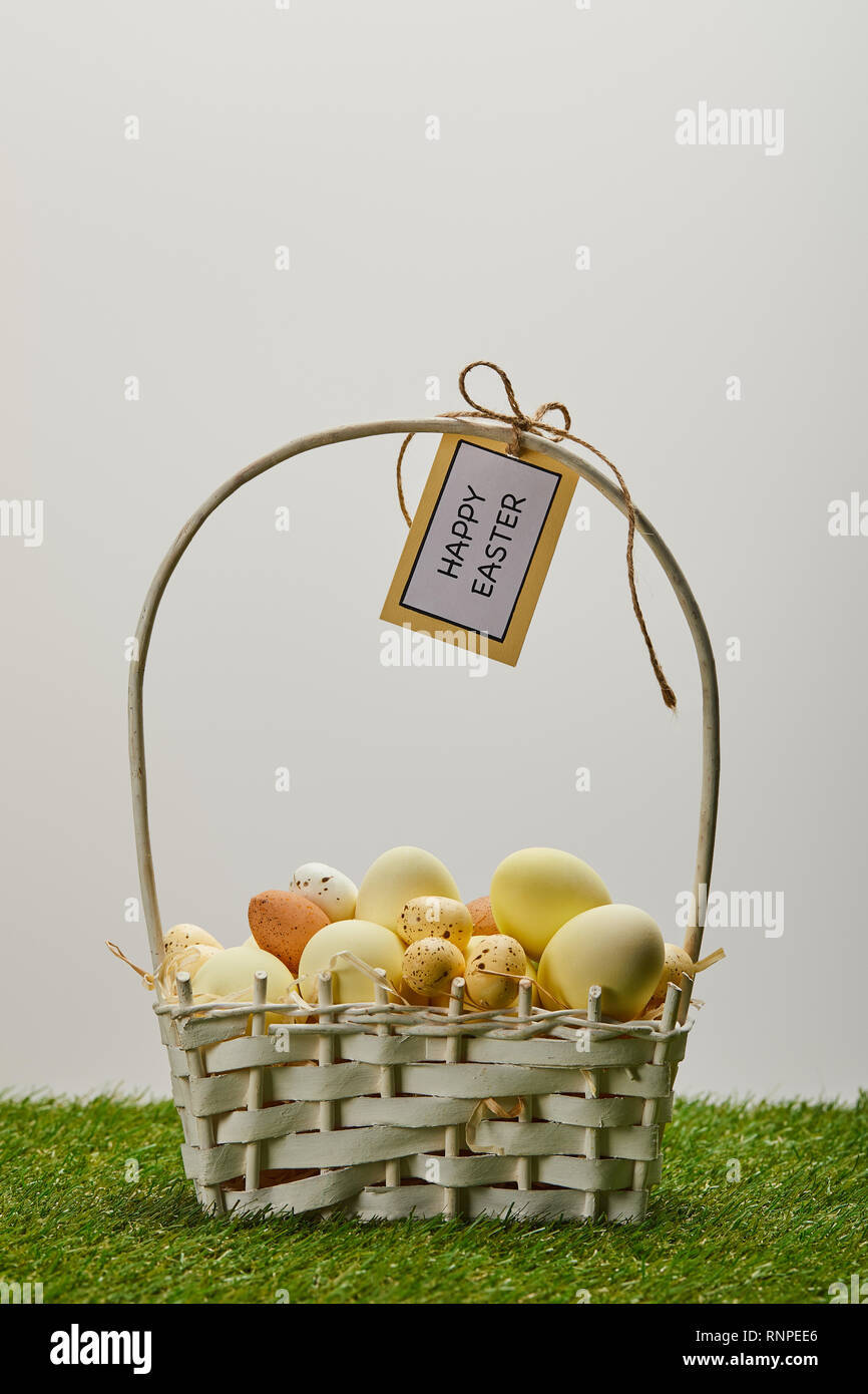 Pasqua pollo e uova di quaglia con cesto di paglia con fiore e scheda con felice Pasqua scritte sull'erba Foto Stock