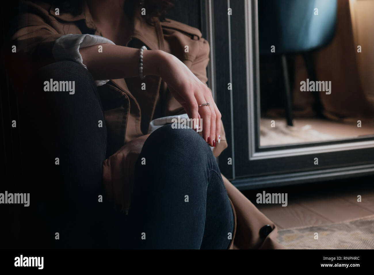 Close-up di uno stile di vita colpo di un elegante donna seduta sul pavimento con la sua mano nella messa a fuoco Foto Stock