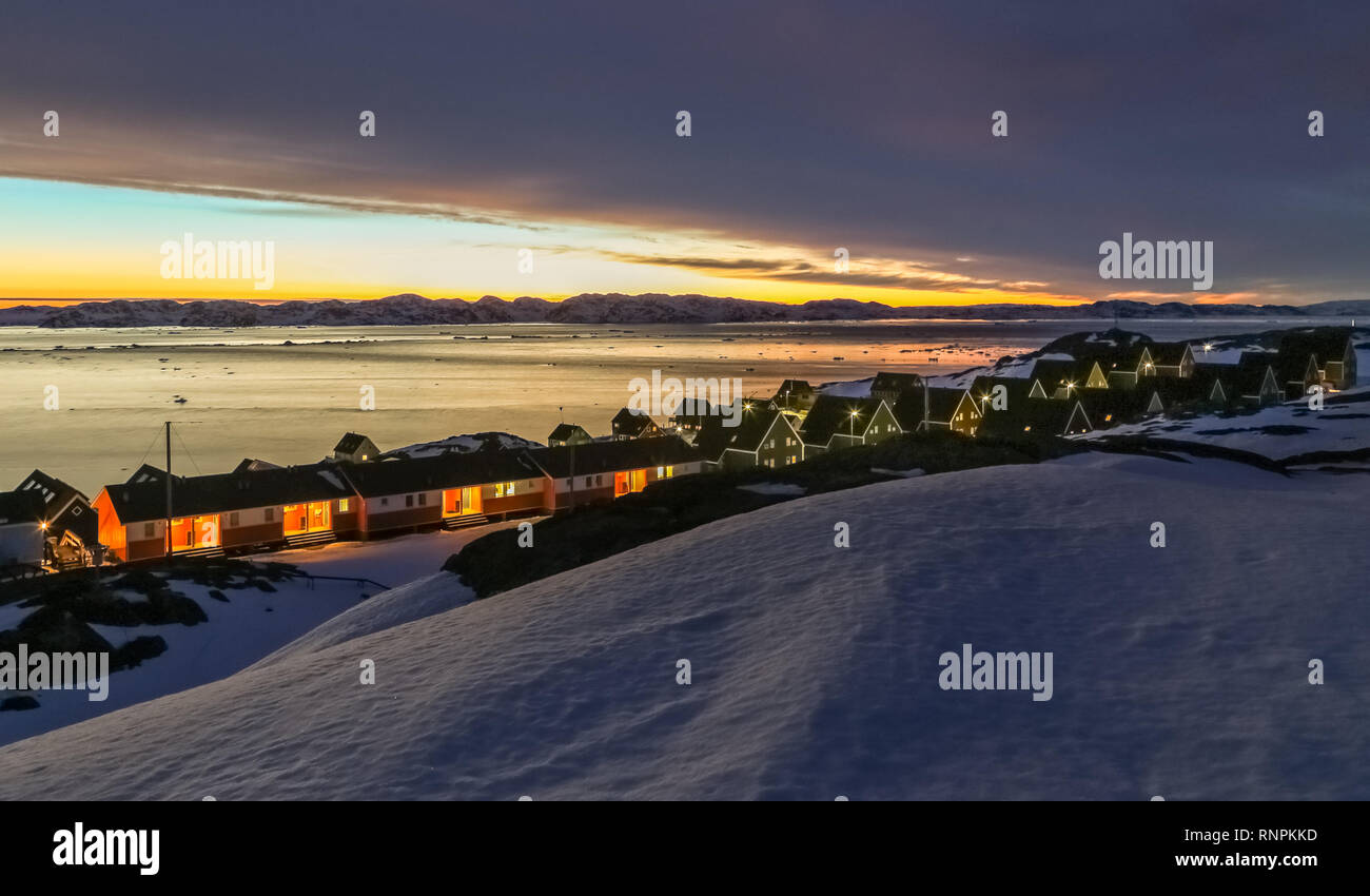 Congelati case inuit tra rocce e neve al tramonto fjord nella periferia della capitale artica Nuuk, Groenlandia Foto Stock