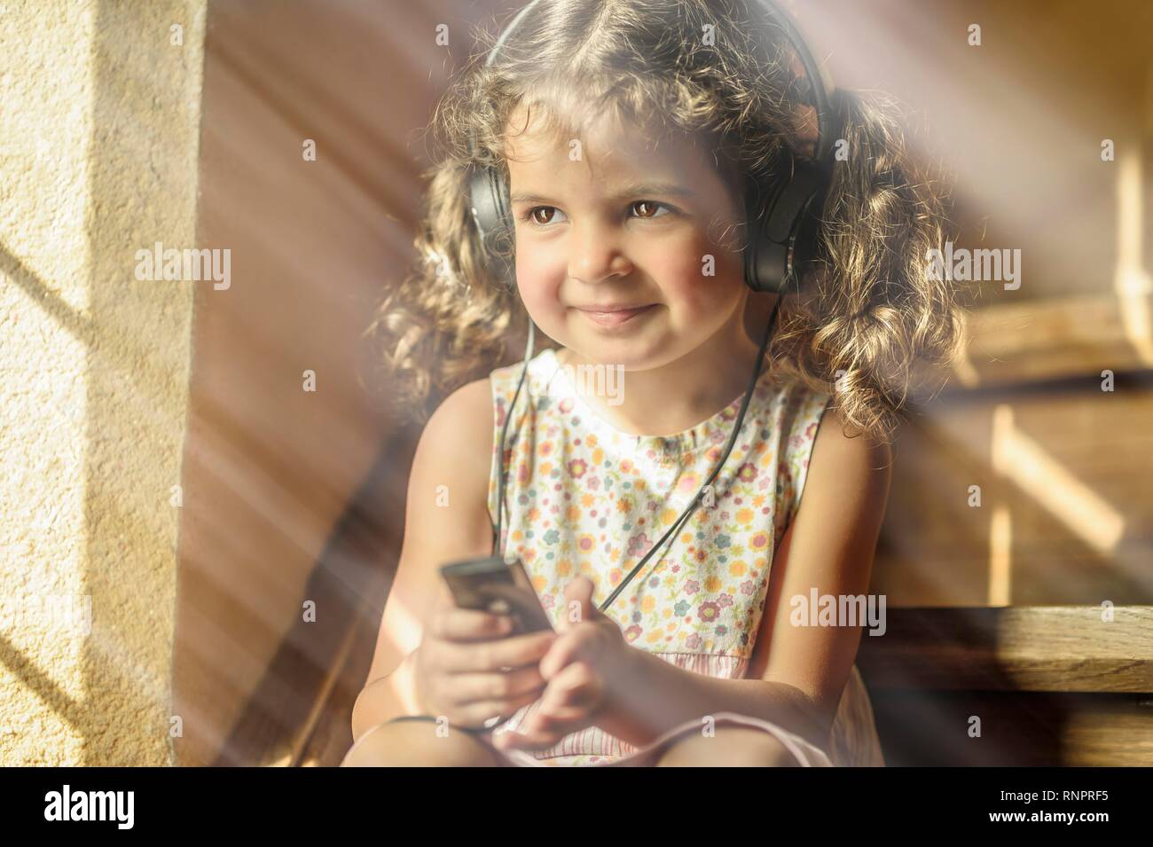 Ragazza 3 anni, ascolta la musica con le cuffie, è felice, Germania Foto Stock