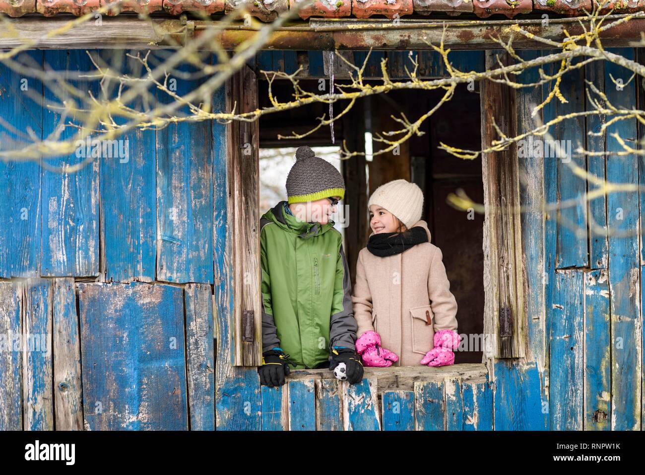 Ragazza 4 anni, boy, 10 anni, i fratelli davanti alla finestra in una capanna in legno, Baden-Württemberg, Germania Foto Stock