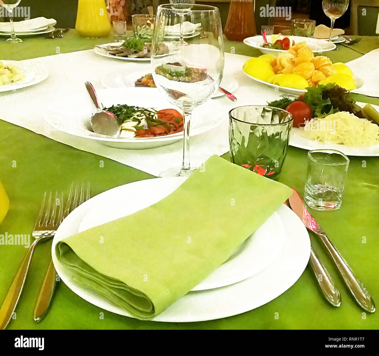 Bella tavola servita con verde e bianco di tovaglioli e tovaglia