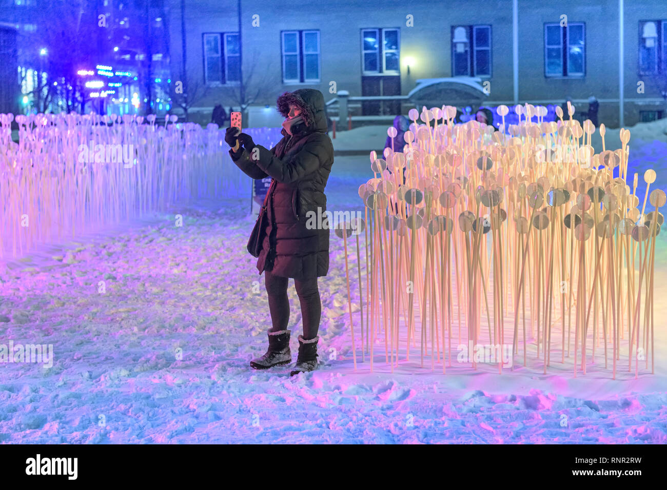 Giovane donna prendendo un selfie foto in centro a Calgary durante la candela di Downtown Winter Light Festival Foto Stock