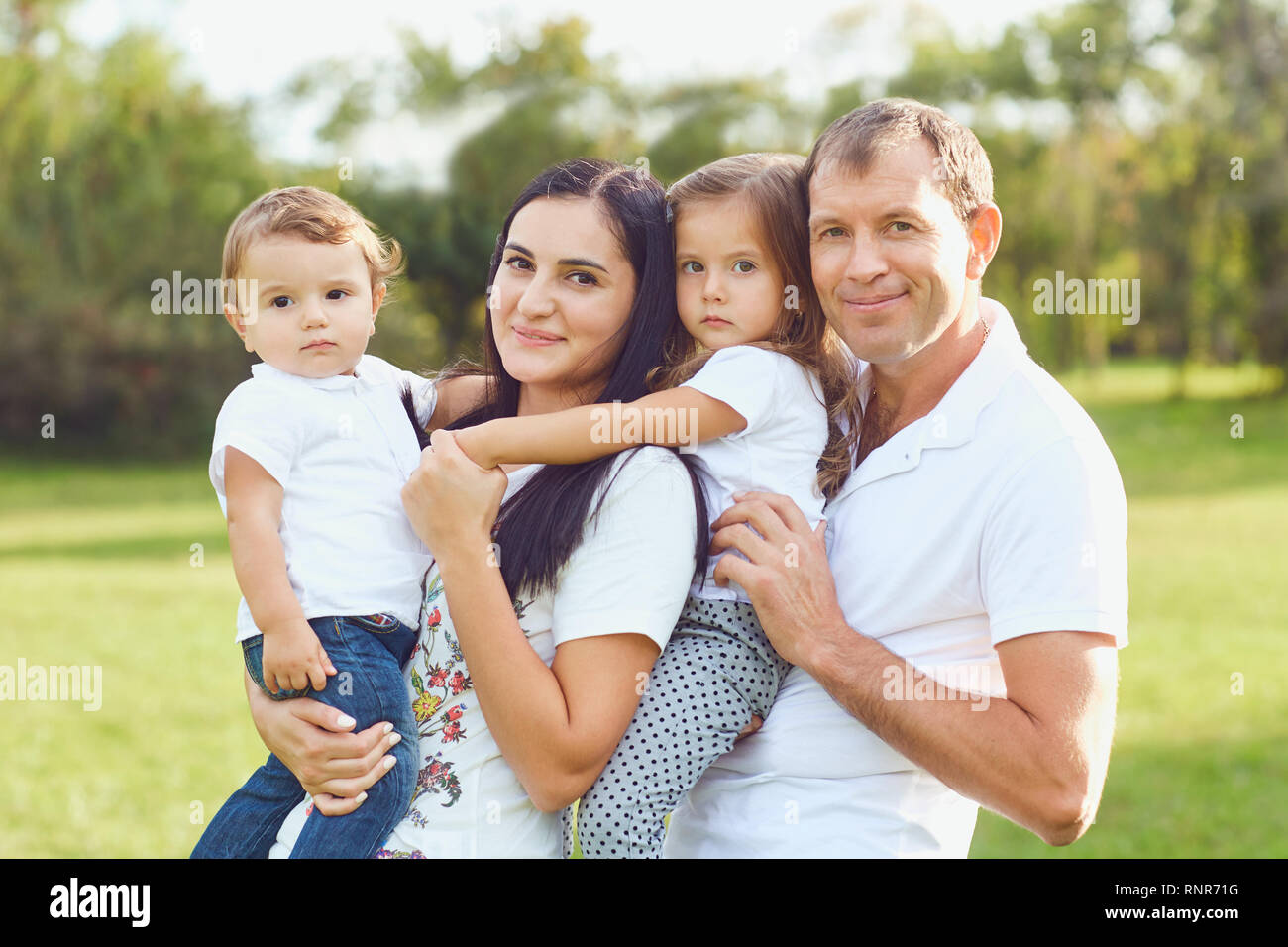 La famiglia felice con bambini sorridenti nel parco. Foto Stock