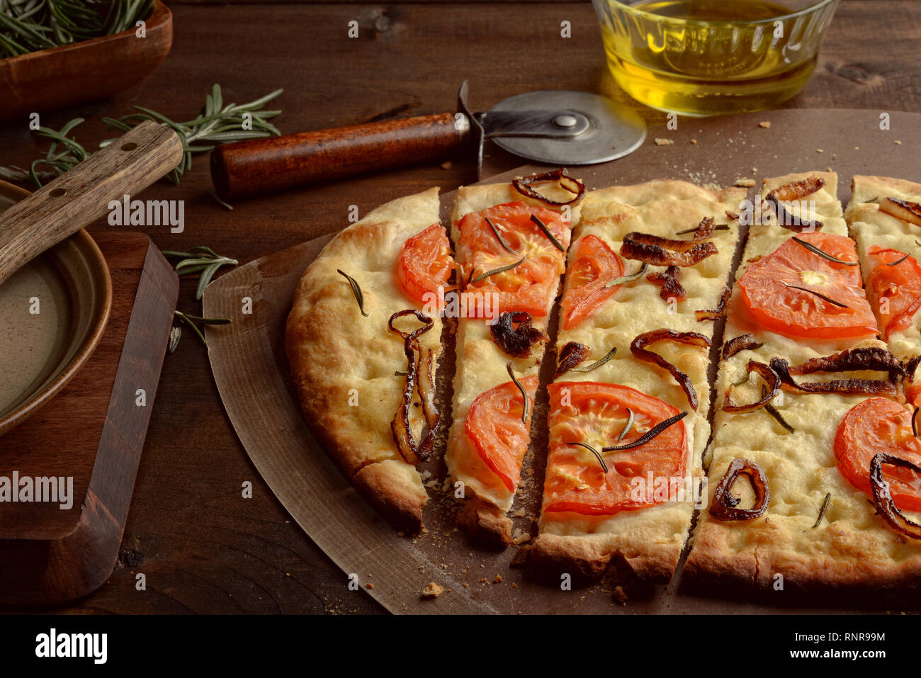 Primo piano di fettine di focaccia con le cipolle caramellate pomodori e di rosmarino fresco Foto Stock