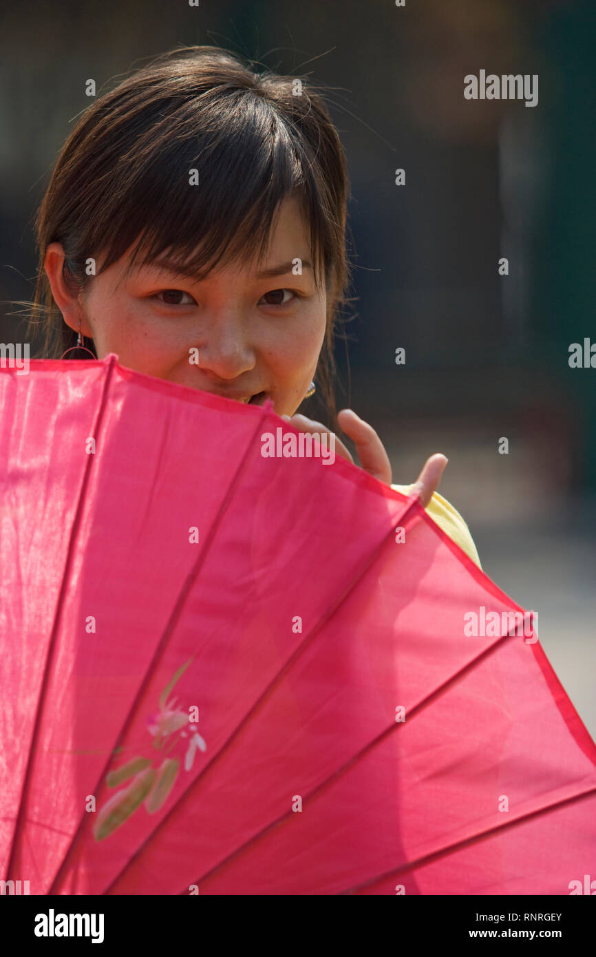 Ritratto di un sorridente giovane donna tenendo un ventilatore. Foto Stock