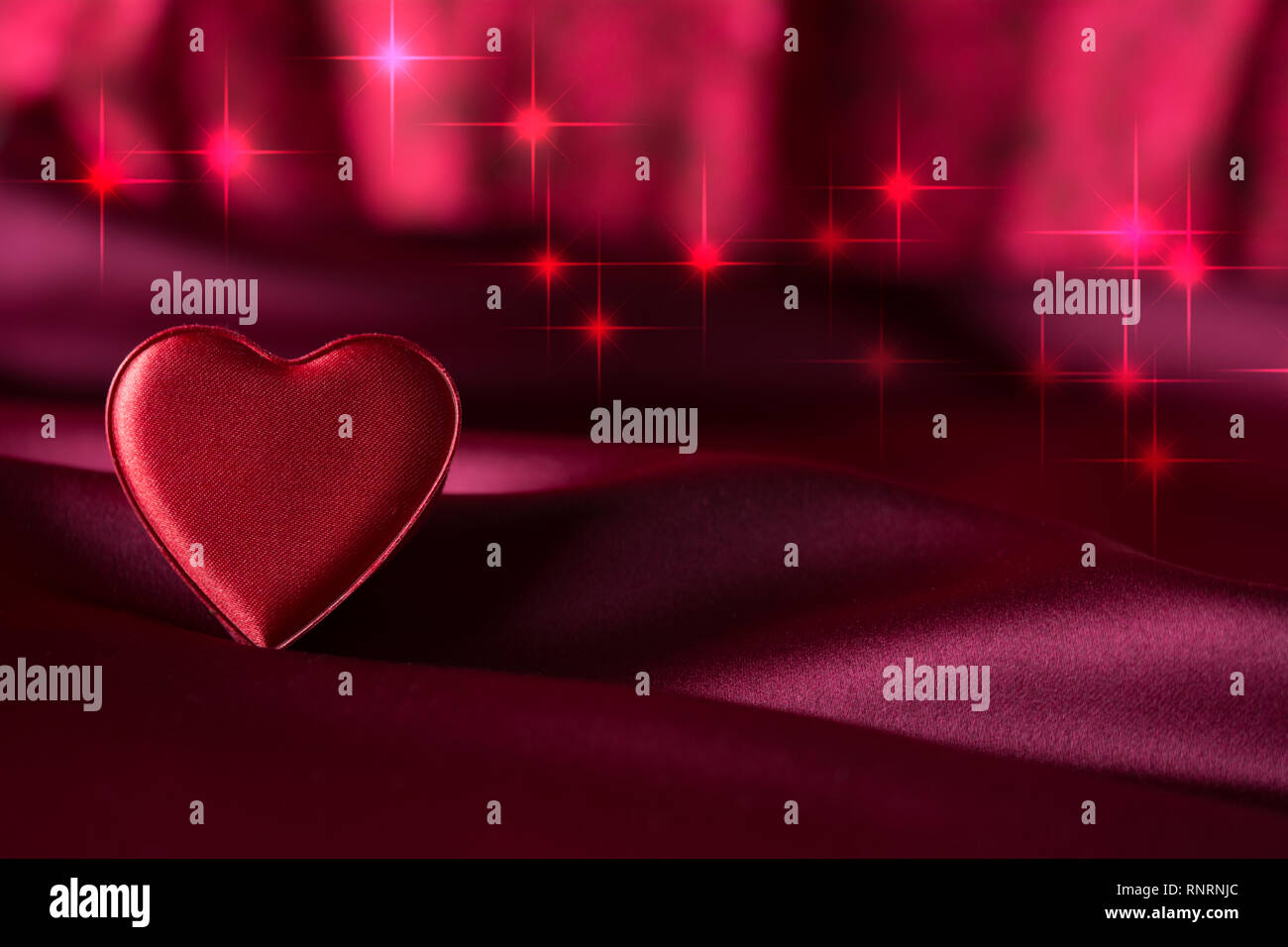 Singolo isolato cuore rosso in raso color porpora - stelle rosse bokeh in background Foto Stock