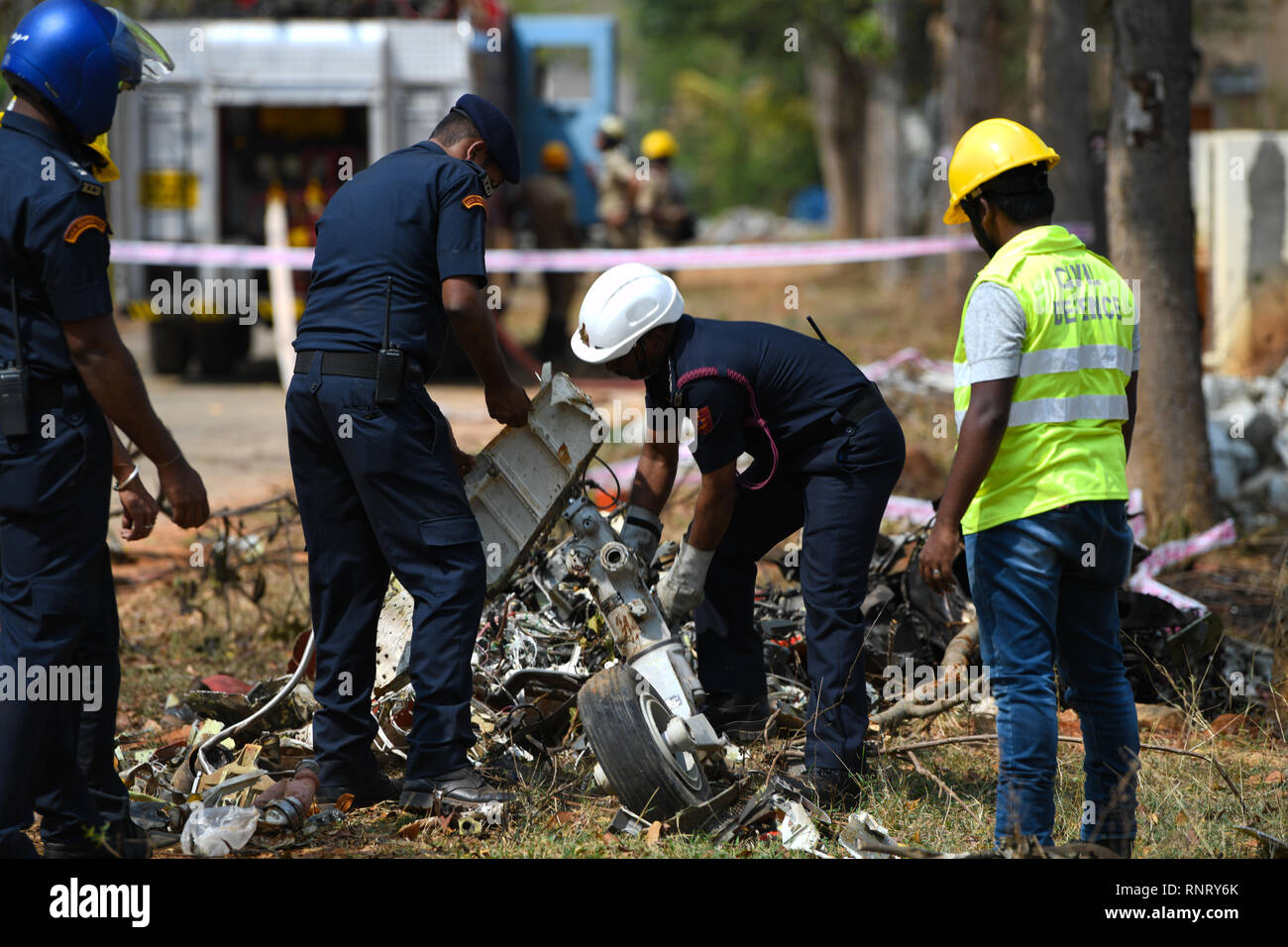 I funzionari sono visto cercando di eliminare i detriti di 1 dei 2 Surya Kiran che si è schiantato in Bengaluru durante una sessione di prove libere prima dell'aero-show che inizia domani dove 2 piloti sono stati feriti e 1 morti accertati. Foto Stock