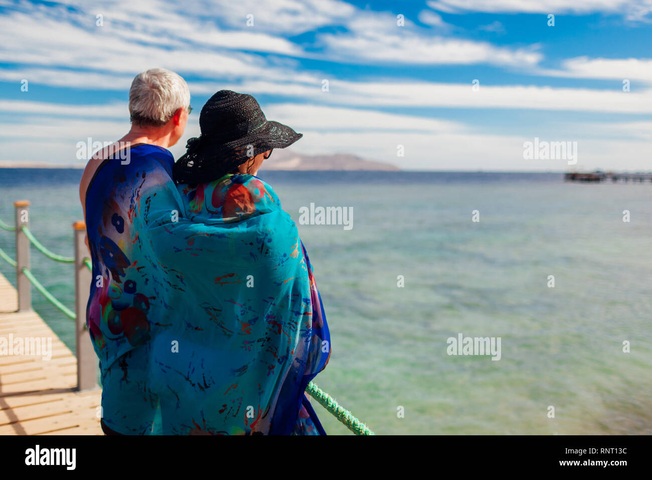 Coppia senior camminando sul molo per mare rosso coperto con pareo. Felici le persone che si godono la vacanza. Il giorno di San Valentino Foto Stock