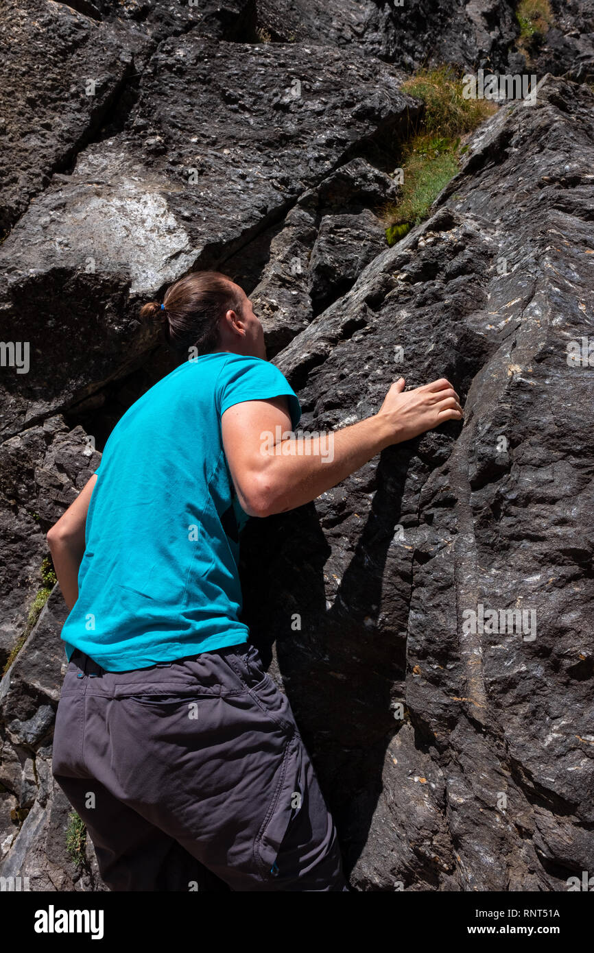 Giovane uomo caucasico è arrampicata su una roccia in Svizzera Foto Stock