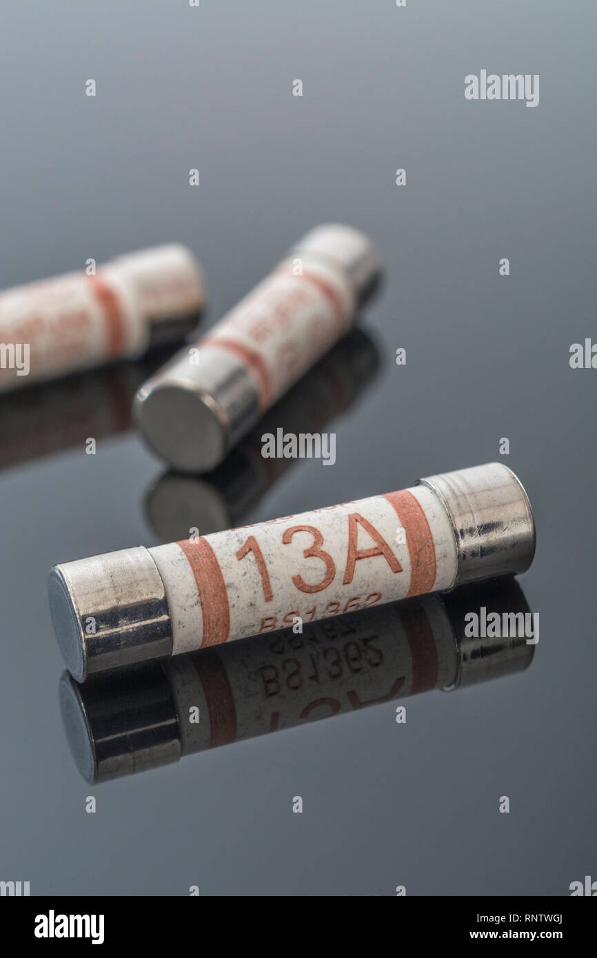 Elettrodomestico elettrico Amp 13 fusibili (cartuccia ceramica tipo) riflettente su sfondo nero. Metafora della sicurezza elettrica. 25mm L x 6,3 mm D Foto Stock