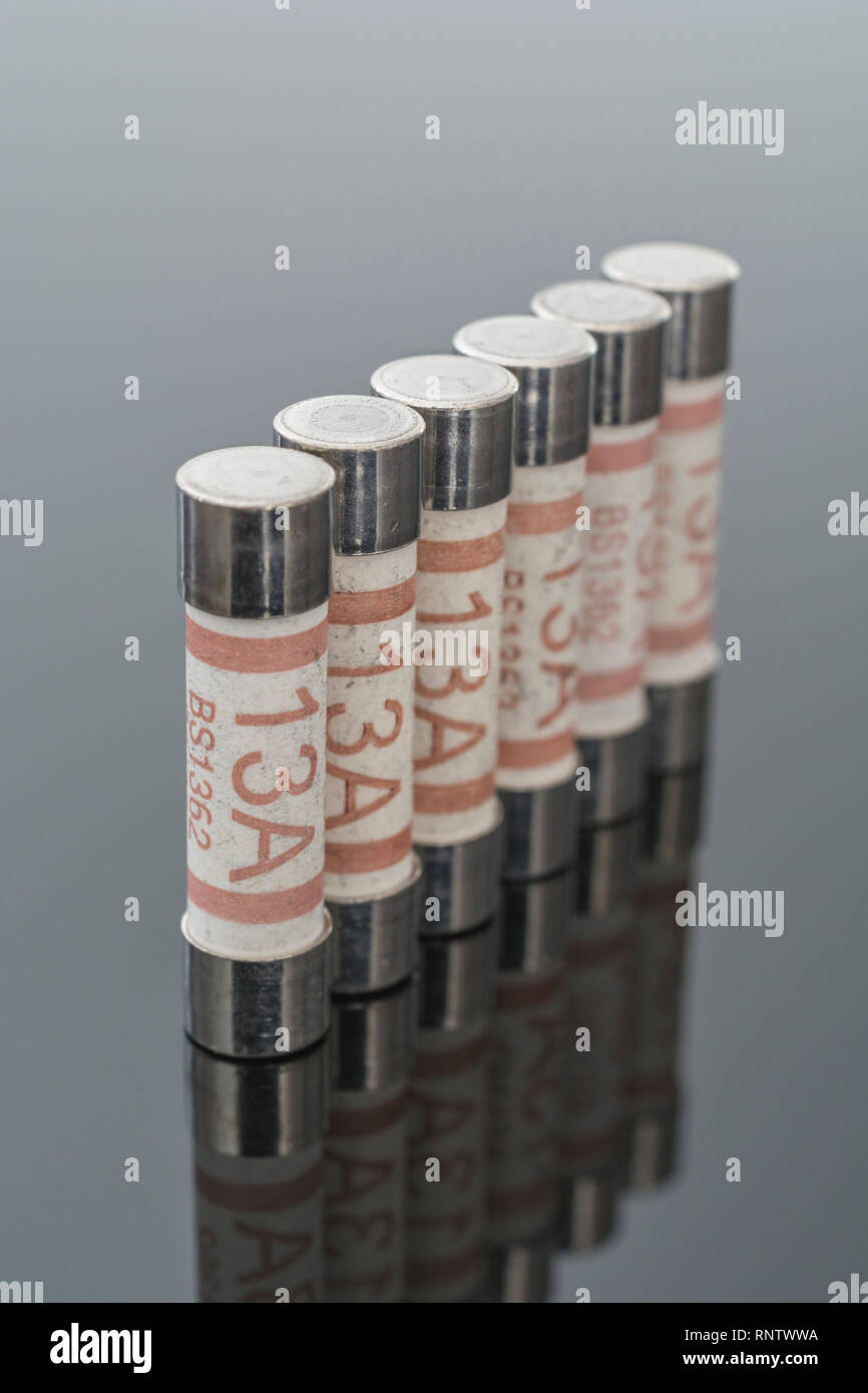 Elettrodomestico elettrico Amp 13 fusibili (cartuccia ceramica tipo) riflettente su sfondo nero. Metafora della sicurezza elettrica. 25mm L x 6,3 mm D Foto Stock