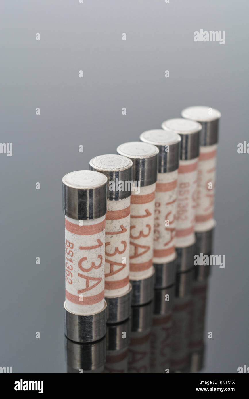 Elettrodomestico elettrico Amp 13 fusibili (cartuccia ceramica tipo) riflettente su sfondo nero. Metafora della sicurezza elettrica. 25mm L x 6,3 mm D Foto Stock