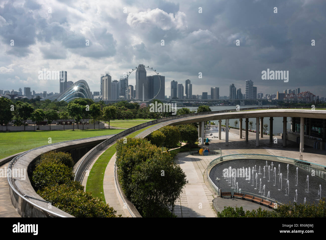 Una tempesta si avvicina la città di Singapore visto dalla Marina Barrage dam mostra eleganti rampe di cemento e fontane. Foto Stock