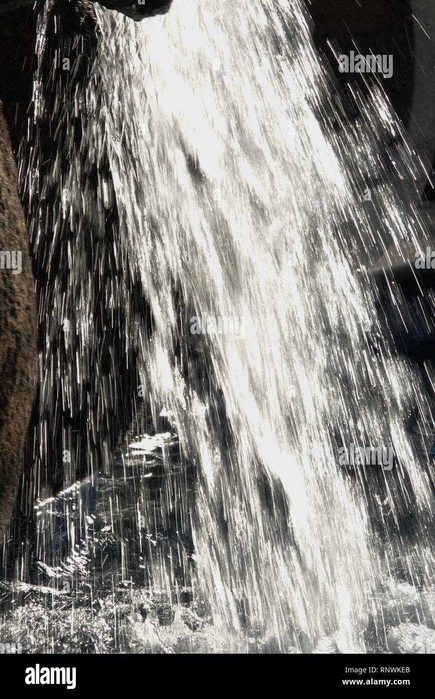 Una vista ravvicinata di un flusso di acqua in una sfocatura da una cascata da un lungo la velocità dello shutter di esposizione. Foto Stock