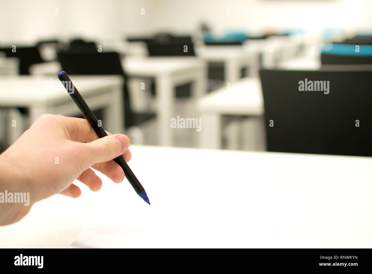 Aula vuota. La scuola superiore o universitario degli studenti tenendo la penna scrittura su carta foglio di risposta. Esame della camera di prova Foto Stock